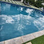 Clear pool water with stone coping and a grass-paver deck